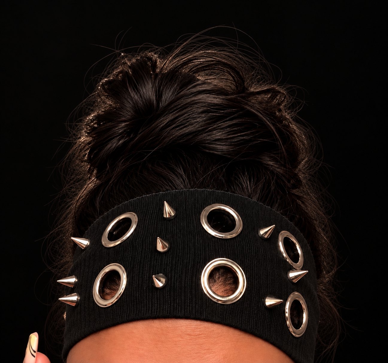 Black spiked headband with silver eyelets worn with a high bun