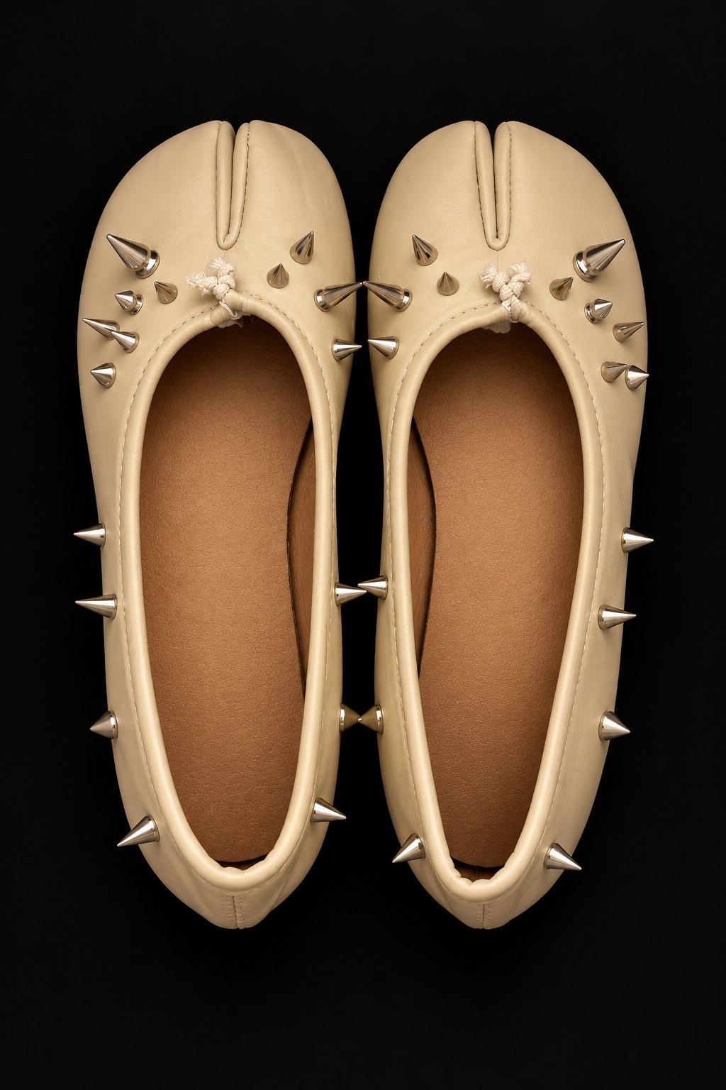 Cream spiked Tabi flats with silver spikes viewed from above on black